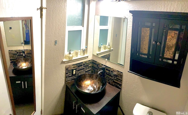 bathroom with vanity, toilet, and decorative backsplash