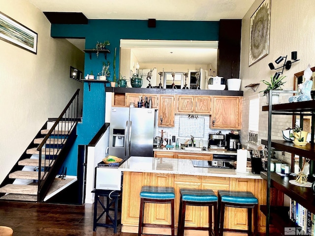 kitchen with a kitchen breakfast bar, kitchen peninsula, dark hardwood / wood-style flooring, and stainless steel fridge with ice dispenser