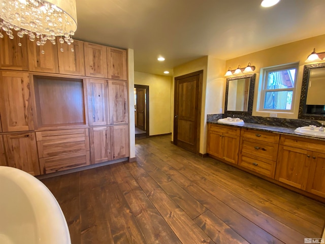 bathroom featuring wood-type flooring, vanity, a chandelier, and a bath