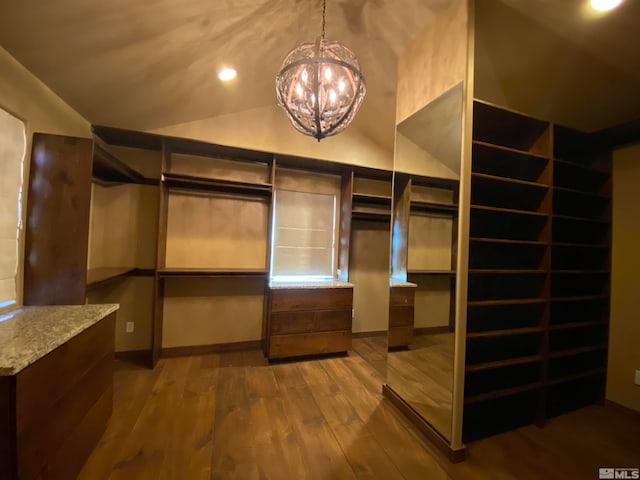 walk in closet with hardwood / wood-style flooring, lofted ceiling, and a notable chandelier