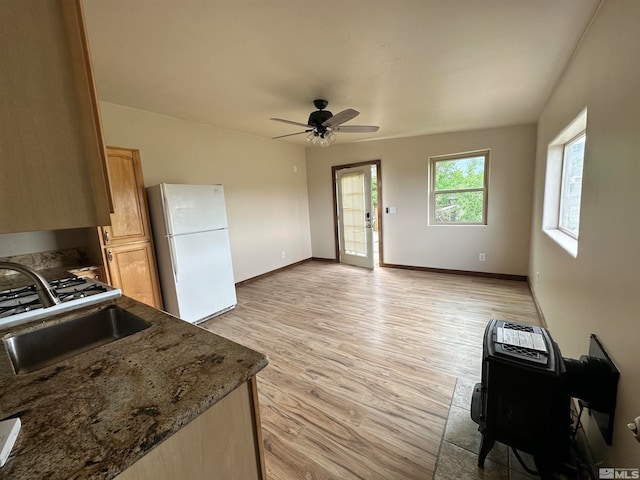 kitchen with dark stone counters, light hardwood / wood-style floors, sink, white fridge, and ceiling fan