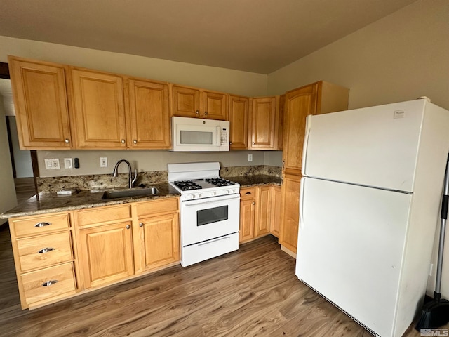 kitchen with sink, vaulted ceiling, white appliances, hardwood / wood-style floors, and dark stone countertops