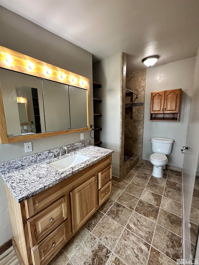 bathroom featuring tiled shower, vanity, and toilet