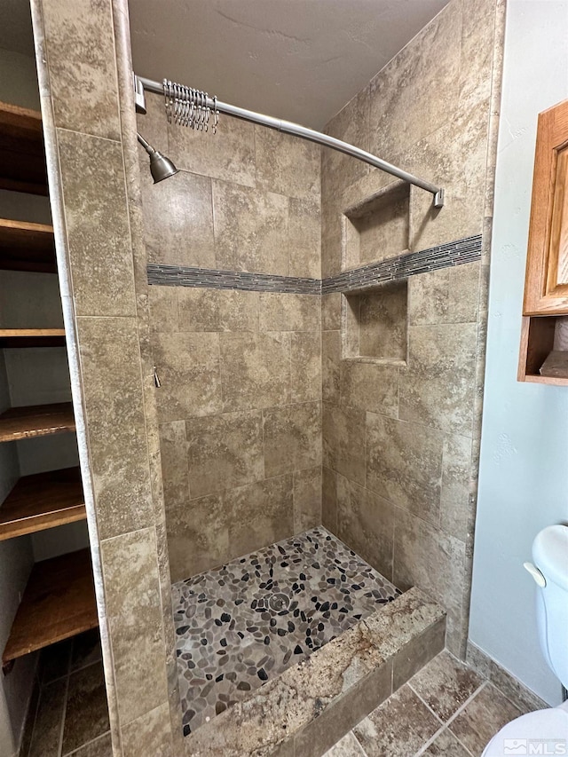 bathroom with toilet and a tile shower