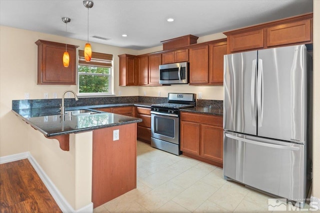 kitchen with dark stone counters, sink, kitchen peninsula, stainless steel appliances, and decorative light fixtures