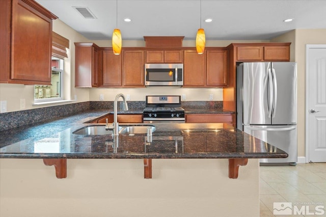 kitchen with decorative light fixtures, appliances with stainless steel finishes, and a kitchen bar