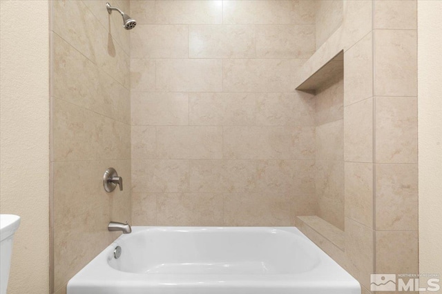 bathroom featuring toilet and tiled shower / bath