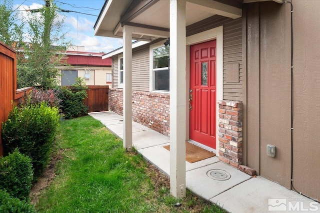 entrance to property featuring a lawn and covered porch