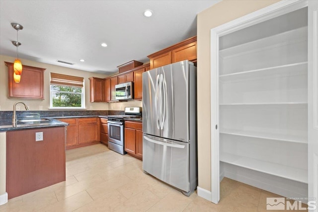 kitchen featuring appliances with stainless steel finishes, hanging light fixtures, sink, and light tile patterned floors