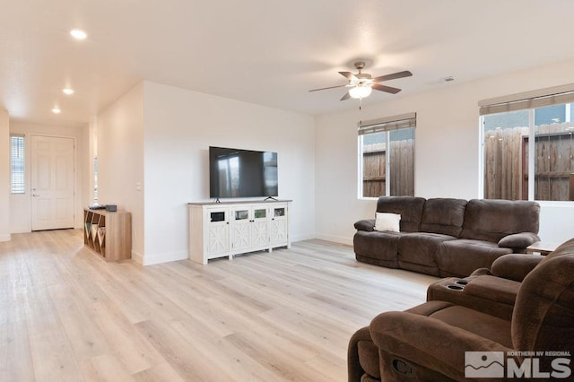 living room with light hardwood / wood-style floors, ceiling fan, and plenty of natural light