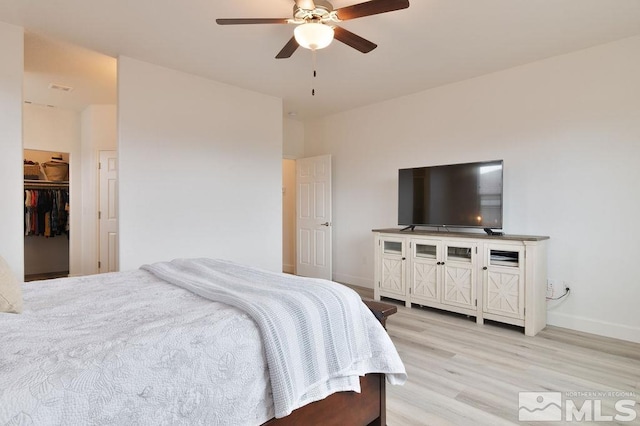 bedroom with ceiling fan, light wood-type flooring, a closet, and a walk in closet