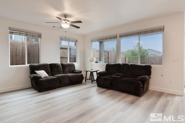 living room featuring light wood-type flooring, ceiling fan, and plenty of natural light