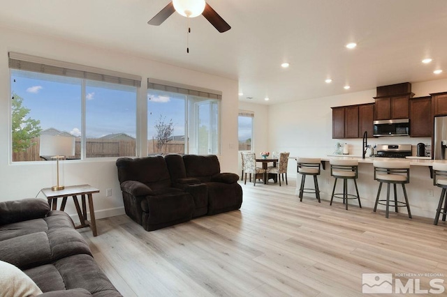 living room with light hardwood / wood-style floors and ceiling fan