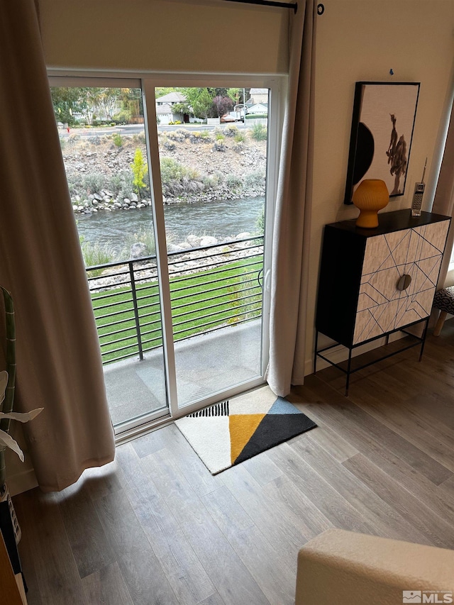 doorway with a water view and hardwood / wood-style floors