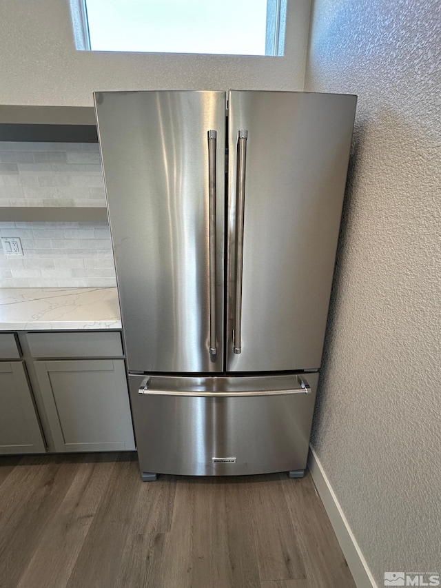 room details with light stone counters, high end fridge, dark wood-type flooring, and gray cabinetry