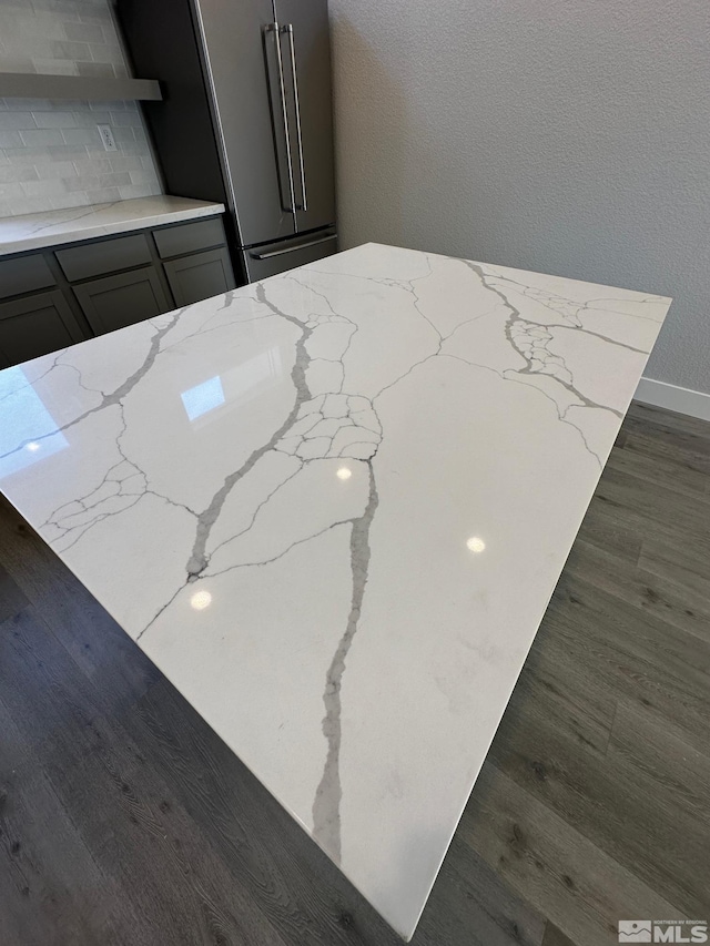 details with gray cabinetry, high quality fridge, dark wood-type flooring, and light stone counters