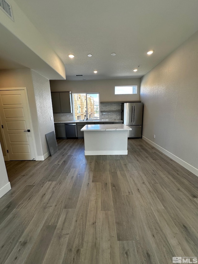 kitchen with stainless steel appliances, a center island, hardwood / wood-style floors, and sink