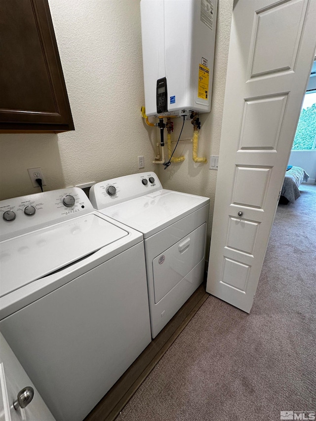 washroom with light carpet, water heater, cabinets, and washer and dryer