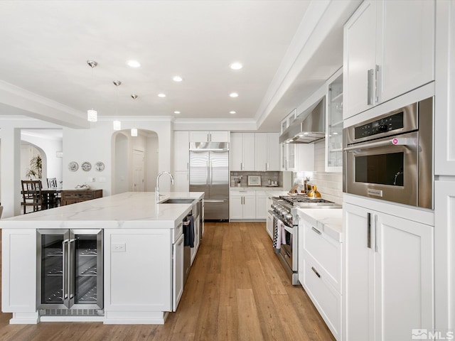 kitchen featuring a center island with sink, high quality appliances, beverage cooler, and white cabinetry