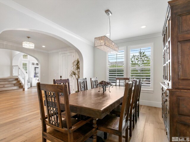 dining area with light hardwood / wood-style flooring, a notable chandelier, and crown molding