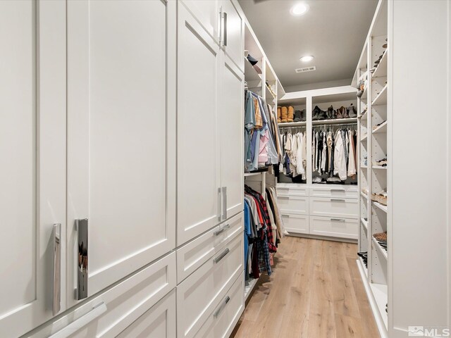 walk in closet with light hardwood / wood-style floors