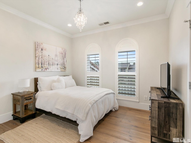 bedroom with ornamental molding, a chandelier, and light hardwood / wood-style floors