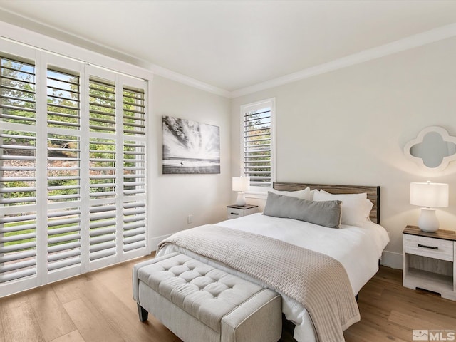 bedroom with multiple windows, light hardwood / wood-style floors, and ornamental molding