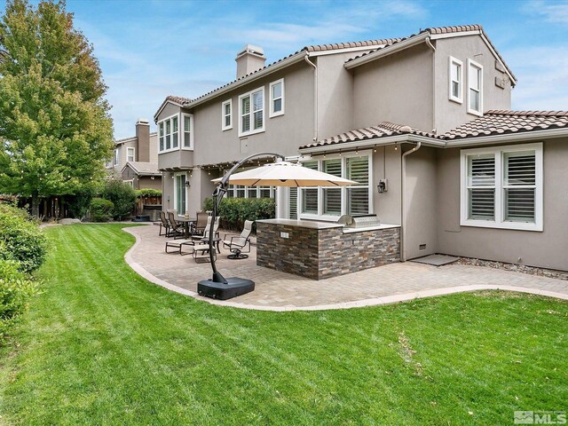 rear view of house featuring a lawn and a patio area