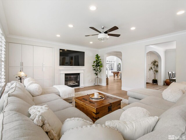 living room featuring light hardwood / wood-style flooring, ceiling fan, and crown molding