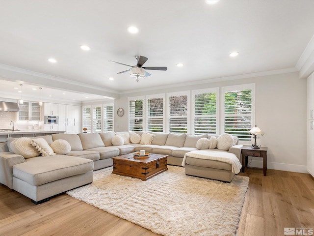 living room with light hardwood / wood-style flooring, ceiling fan, sink, and crown molding