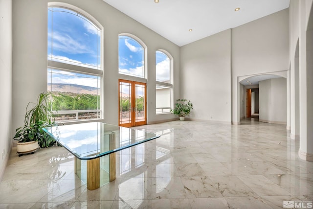 spare room with french doors and high vaulted ceiling