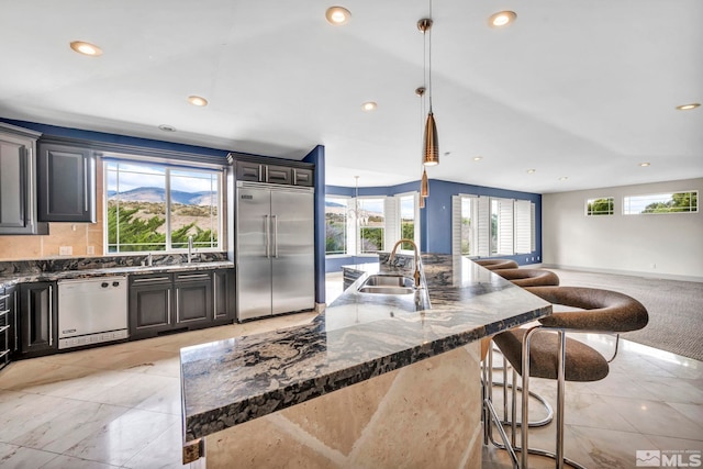 kitchen with a large island, pendant lighting, sink, a kitchen breakfast bar, and stainless steel appliances