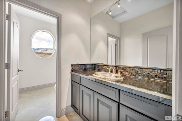 bathroom featuring tile patterned flooring, tasteful backsplash, rail lighting, vanity, and toilet