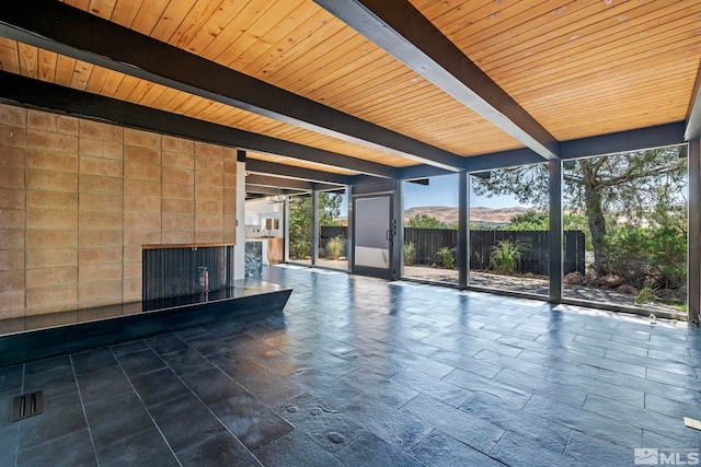 unfurnished living room featuring a fireplace, beam ceiling, wood ceiling, and a mountain view