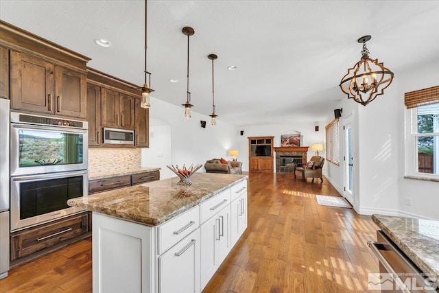 kitchen with pendant lighting, light wood-type flooring, white cabinetry, stainless steel appliances, and light stone countertops