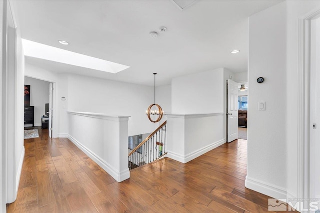 hallway with wood-type flooring and a skylight