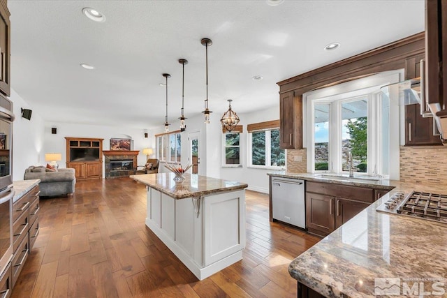 kitchen with light stone countertops, appliances with stainless steel finishes, pendant lighting, and a kitchen island