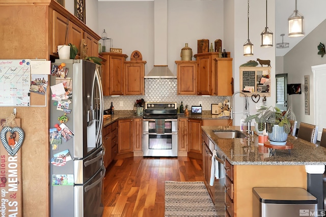 kitchen featuring hanging light fixtures, dark wood-type flooring, stainless steel appliances, a breakfast bar, and dark stone countertops