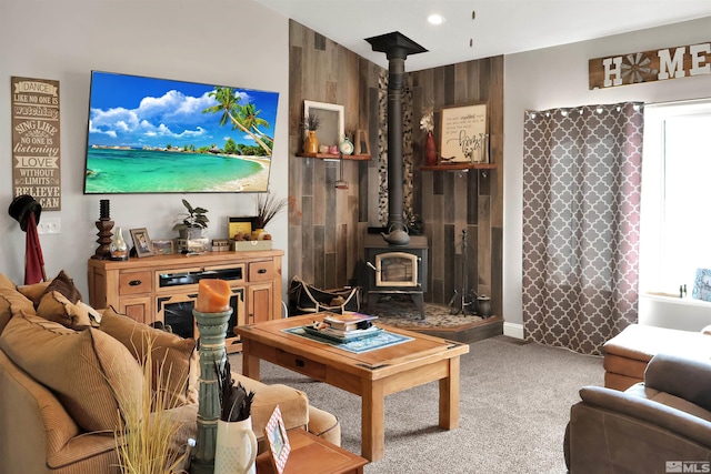 living room featuring carpet, wood walls, and a wood stove