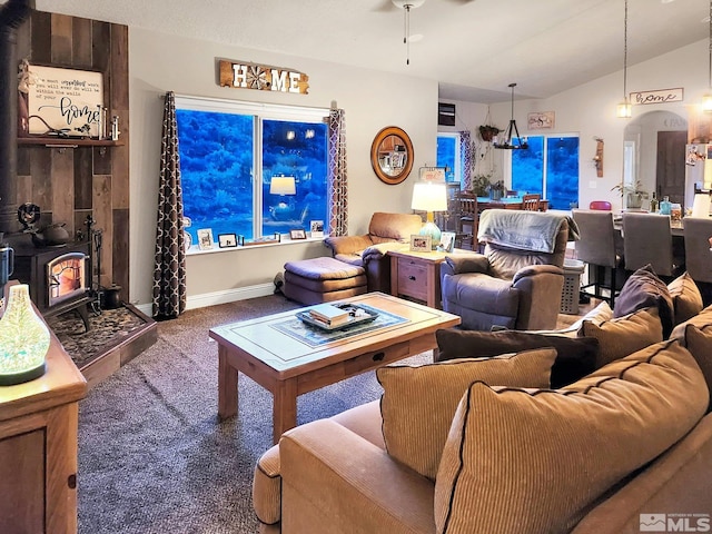 carpeted living room featuring lofted ceiling, ceiling fan, and a wood stove