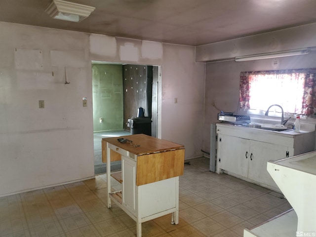 kitchen with sink, butcher block countertops, white cabinetry, a center island, and a breakfast bar area