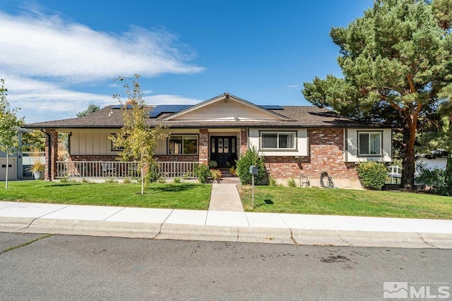 ranch-style home featuring a front yard, solar panels, and a porch