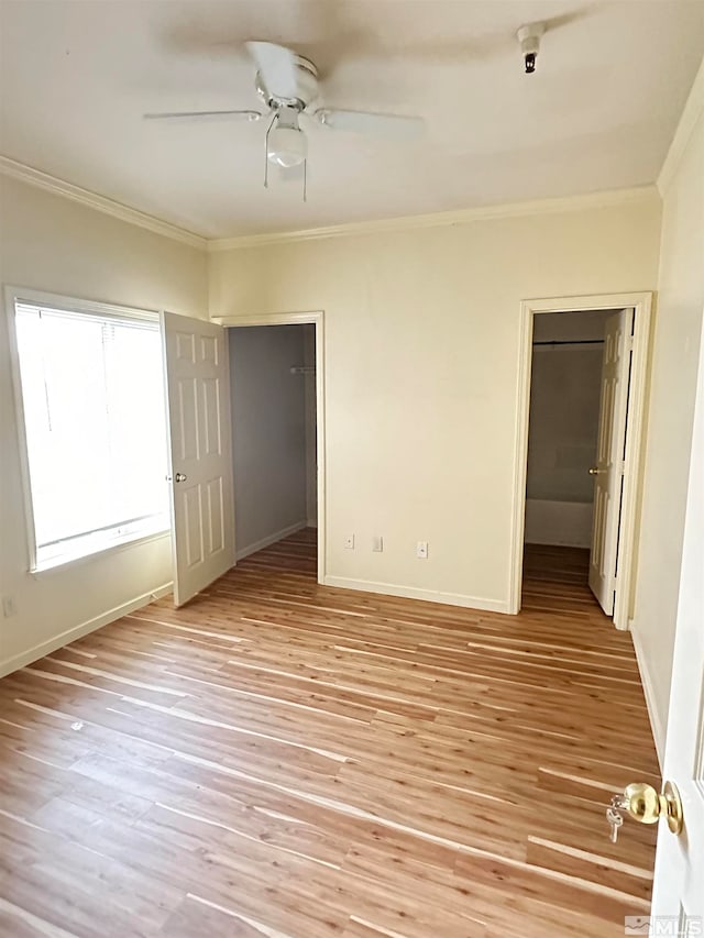 unfurnished bedroom with crown molding, ceiling fan, a spacious closet, and light hardwood / wood-style floors