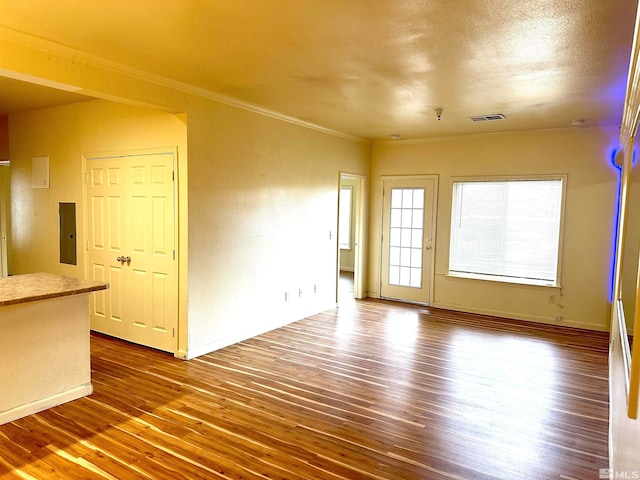 unfurnished living room with hardwood / wood-style flooring, ornamental molding, a textured ceiling, and electric panel