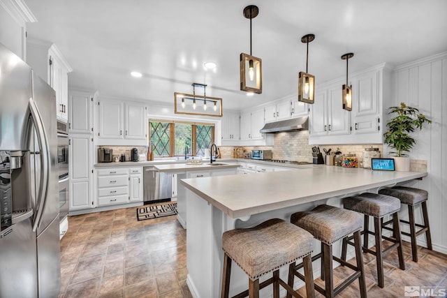 kitchen featuring a breakfast bar, white cabinets, kitchen peninsula, and appliances with stainless steel finishes