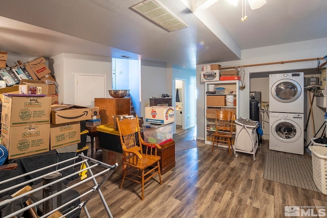 basement featuring wood-type flooring, ceiling fan, and stacked washer / dryer