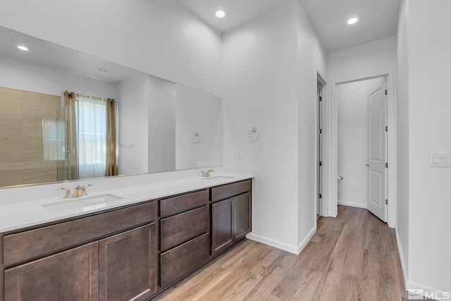 bathroom with wood-type flooring, vanity, and a shower with door