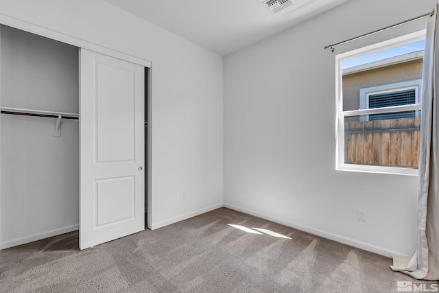 unfurnished bedroom featuring light colored carpet and a closet