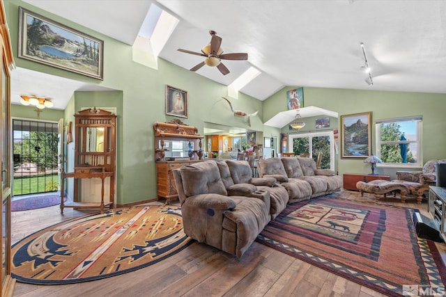 living room featuring ceiling fan, hardwood / wood-style flooring, vaulted ceiling with skylight, and track lighting