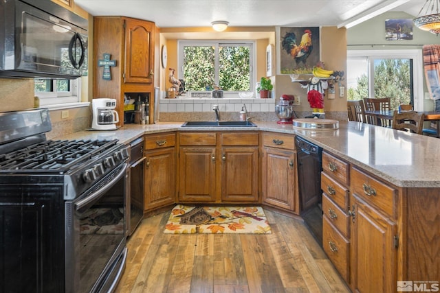 kitchen with black appliances, light hardwood / wood-style floors, plenty of natural light, and sink